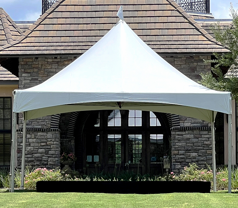 White high peak marquee tent set on a lawn in front of a stone building entrance
