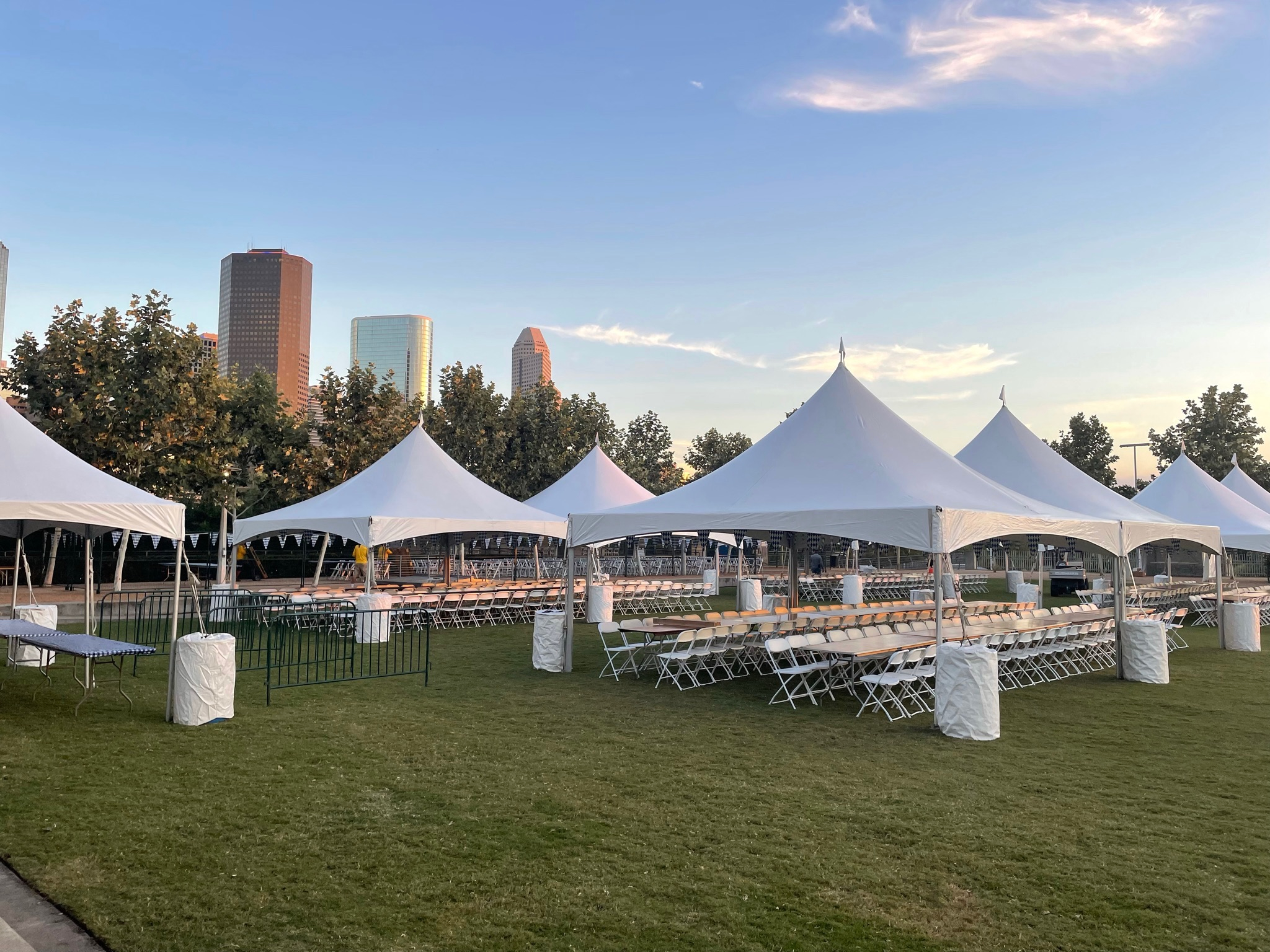 ACME Party and Tent pole tents set up for a Houston-area community event, with the city skyline behind
