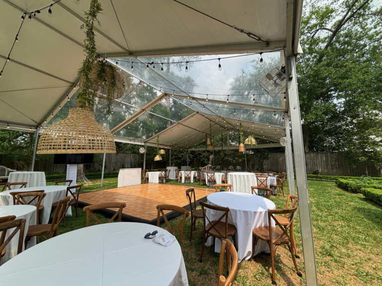 Clear-top backyard tent with farm tables and crossback chairs at a Houston private party