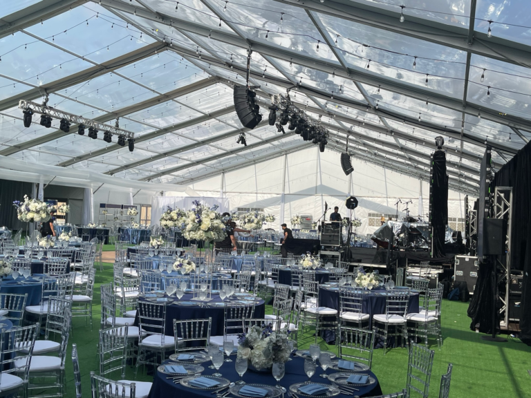 Navy floor-length linens and silver Chiavari chairs set under a clear-top tent at a Houston reception
