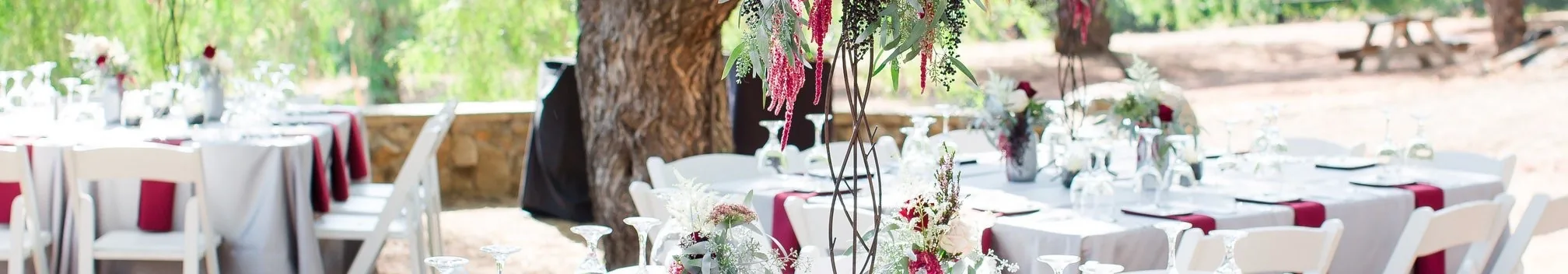 White table linens with magenta napkins and floral centerpieces at an outdoor Houston event