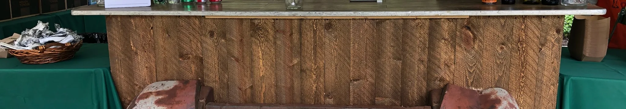 Rustic wood bar front built from a vintage truck grille under an ACME event tent