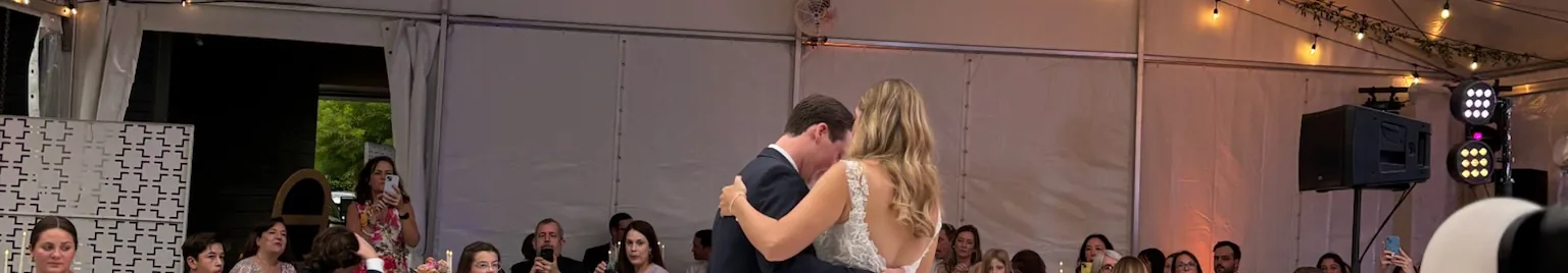 Bride and groom dancing on a checkered dance floor under a clear top tent at a Houston wedding
